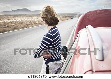 Stock Image - Woman with broken down car on rural road. Fotosearch
