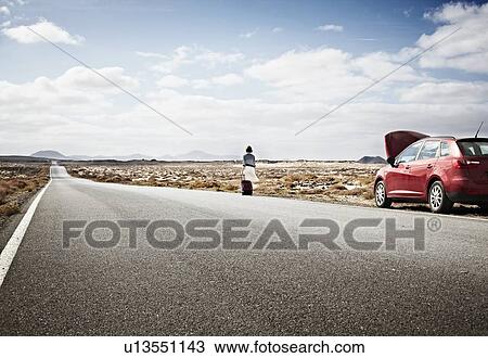 Stock Image - Woman with broken down car on rural road. Fotosearch