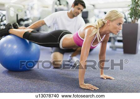 Stock Image - Woman working with trainer in gym. Fotosearch