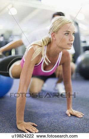 Stock Image - Woman working with trainer in gym. Fotosearch
