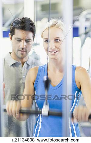 Stock Photo - Woman working with trainer in gym. Fotosearch
