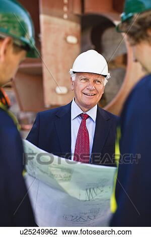 Stock Image - Workers reading blueprints on dry dock. Fotosearch