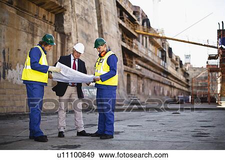 Stock Photo - Workers reading blueprints on dry dock. Fotosearch