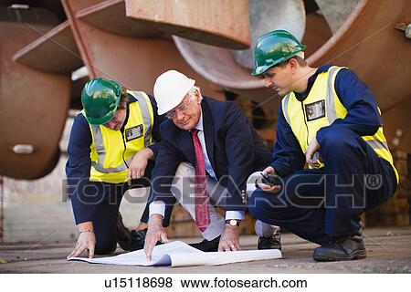 Workers reading blueprints on dry dock View Large Photo Image Stock Photo - Workers reading blueprints on dry dock. Fotosearch