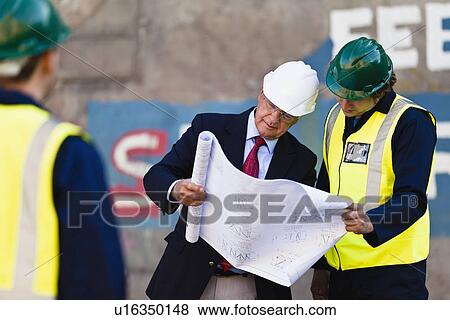 Stock Photo - Workers reading blueprints on dry dock. Fotosearch