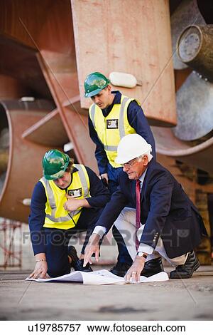 Workers reading blueprints on dry dock View Large Photo Image Stock Photo - Workers reading blueprints on dry dock. Fotosearch