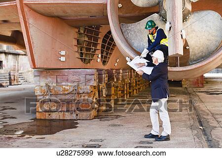 Stock Photo - Workers talking in propeller on dry dock. Fotosearch