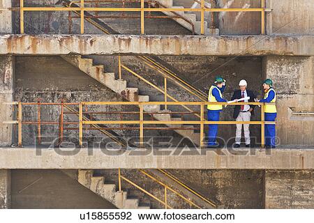 Stock Image - Workers talking on steps on dry dock. Fotosearch