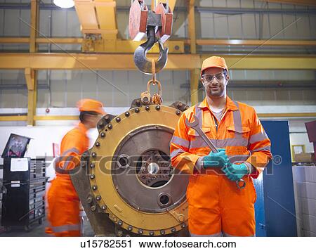 Stock Image - Apprentice engineer holding wrench. Fotosearch
