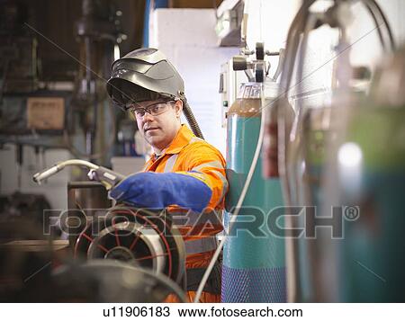 Stock Image - Apprentice engineer welding in factory. Fotosearch