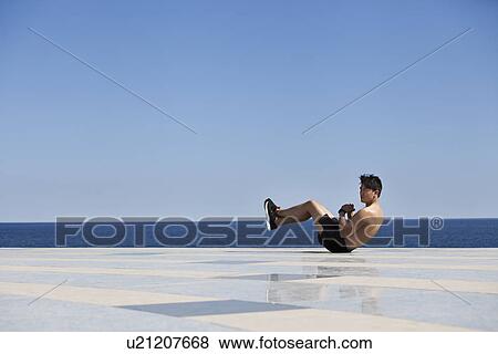Stock Photo - Athlete doing sit-ups on tiled surface. Fotosearch