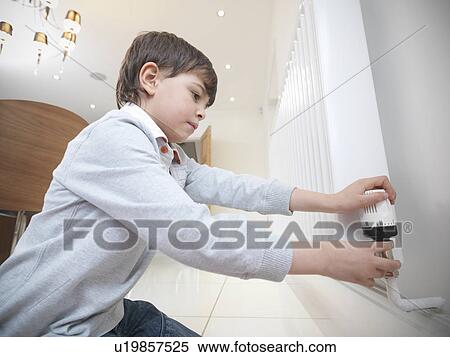 Stock Photography - Boy adjusting radiator in kitchen. Fotosearch