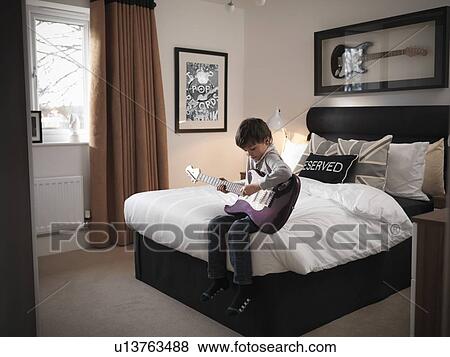 Boy playing guitar in bedroom View Large Photo Image Stock Photo - Boy playing guitar in bedroom. Fotosearch