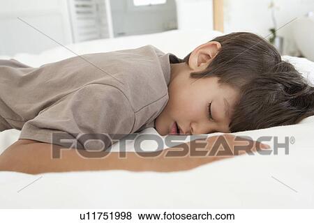 Stock Photo - Boy sleeping on bed. Fotosearch