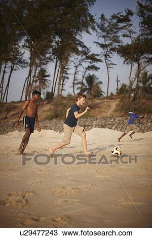 Boys playing soccer on sandy beach View Large Photo Image Stock Image - Boys playing soccer on sandy beach. Fotosearch