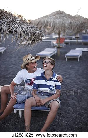 Stock Photography - Brothers laughing together on beach. Fotosearch