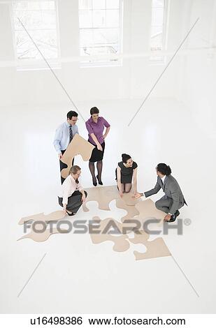 Stock Photograph - Business people doing puzzle in office. Fotosearch