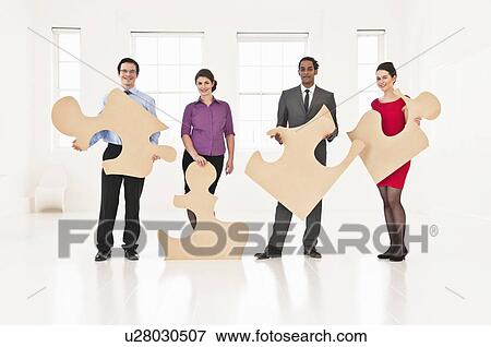 Business people holding puzzle pieces View Large Photo Image Stock Photo - Business people holding puzzle pieces. Fotosearch