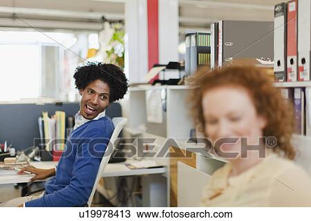 Stock Image - Business people talking at desks. Fotosearch