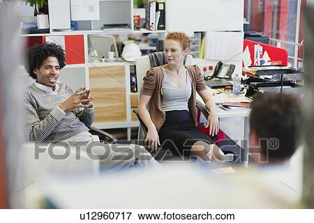 Stock Photo - Business people talking at desks. Fotosearch