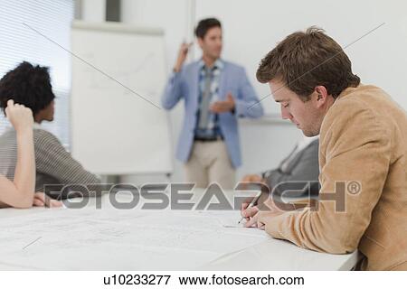 Stock Photo - Businessman making notes in meeting. Fotosearch