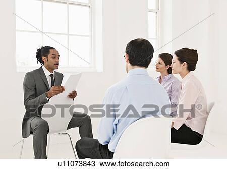 Stock Image - Businessman reading to colleagues. Fotosearch