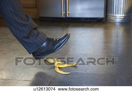 Picture - Businessman stepping on banana peel. Fotosearch