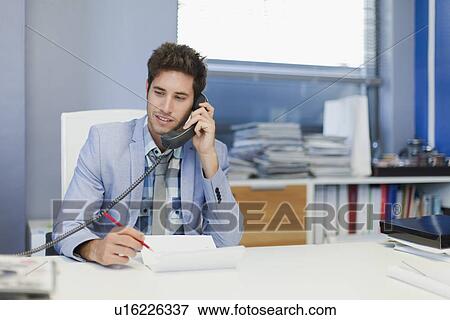 Stock Photo - Businessman talking on phone at desk. Fotosearch
