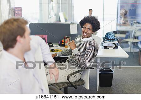 Stock Image - Businessmen talking at desks. Fotosearch