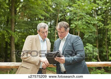 Stock Photo - Businessmen using tablet computer. Fotosearch
