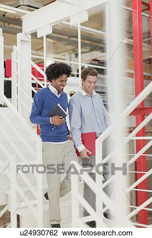 Businessmen walking together in office View Large Photo Image Stock Image - Businessmen walking together in office. Fotosearch