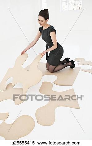 Stock Photography - Businesswoman doing puzzle in office. Fotosearch
