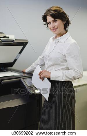 Stock Image - Businesswoman making copies in office. Fotosearch