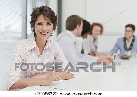 Stock Image - Businesswoman making notes in meeting. Fotosearch