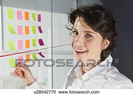 Stock Image - Businesswoman peeling off sticky note. Fotosearch