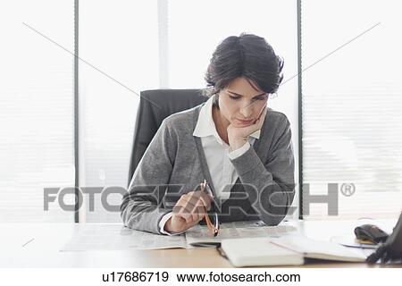 Stock Photo - Businesswoman reading newspaper at desk. Fotosearch