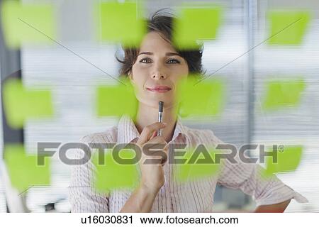 Stock Image - Businesswoman reading sticky notes. Fotosearch