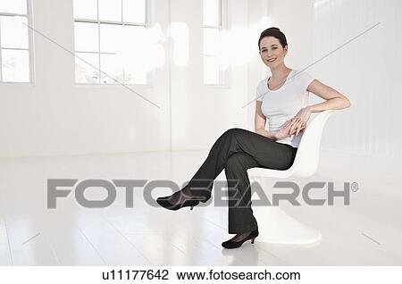 Stock Image - Businesswoman sitting in lobby area. Fotosearch