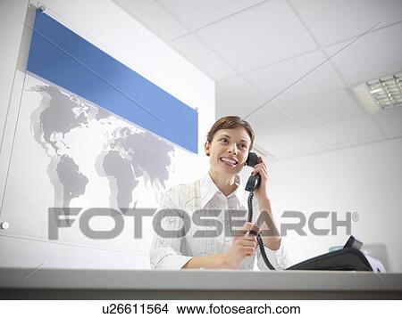 Picture - Businesswoman talking on phone at desk. Fotosearch