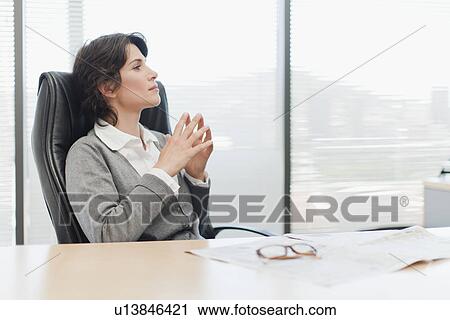Stock Image - Businesswoman thinking at desk. Fotosearch
