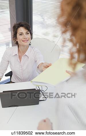 Stock Image - Businesswoman turning in folder to boss. Fotosearch