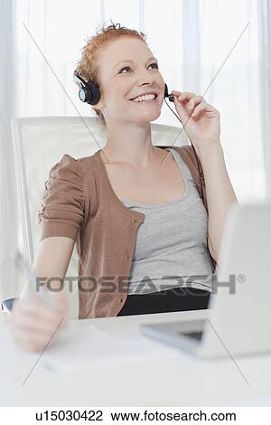 Businesswoman wearing headset at desk View Large Photo Image Stock Image - Businesswoman wearing headset at desk. Fotosearch