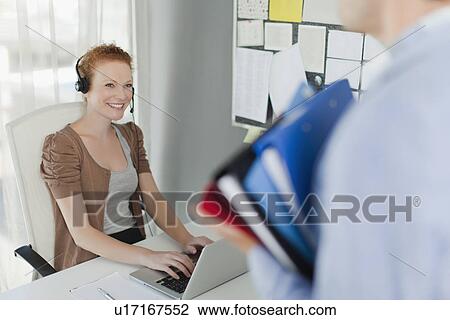 Businesswoman wearing headset at desk View Large Photo Image Stock Image - Businesswoman wearing headset at desk. Fotosearch
