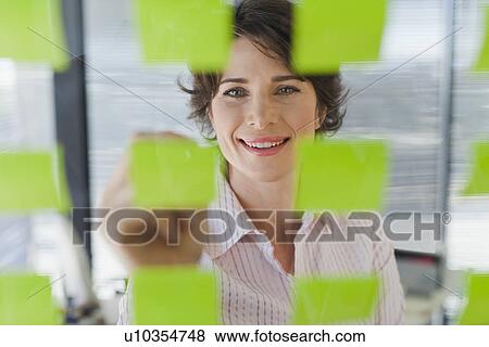 Stock Photo - Businesswoman writing on sticky notes. Fotosearch