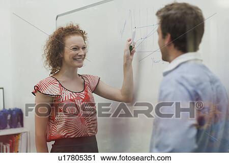 Stock Image - Businesswoman writing on whiteboard. Fotosearch