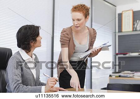 Businesswomen talking in office View Large Photo Image Stock Photograph - Businesswomen talking in office. Fotosearch