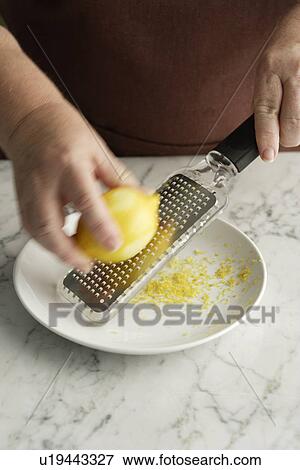 Stock Photo - Chef grating lemon in bowl. Fotosearch