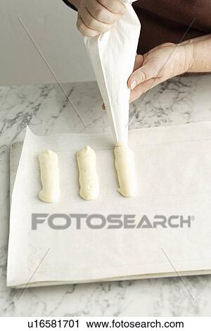 Stock Image - Chef piping dough on cookie sheet. Fotosearch