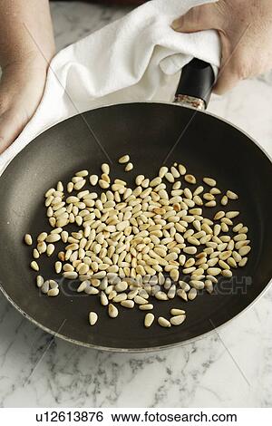 Chef toasting pine nuts in pan View Large Photo Image Stock Photograph - Chef toasting pine nuts in pan. Fotosearch