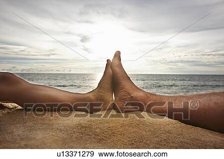 Stock Photo - Close up of feet touching on beach. Fotosearch